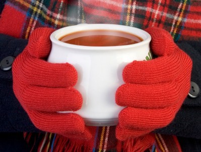 A woman with gloves holding a bowl of hot tomato soup.
