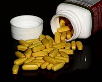 A container with B vitamin supplement pills spilling out.