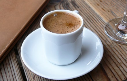 A cup of coffee on a wooden table.