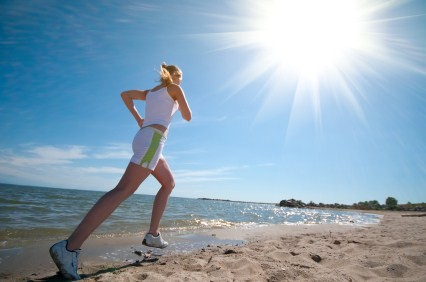 A woman running on a sunny beach.