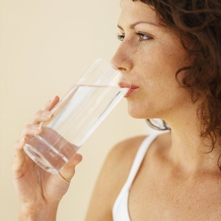 A woman drinking a glass of water.