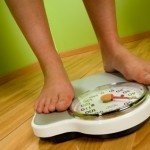 A person weighing themselves on a pair of weighing scales.