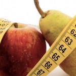 An apple and a pair wrapped in a tape measure.
