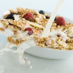 A bowl of fruit and muesli being splashed with milk.