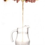 Corn oil being squeezed into a glass jug.