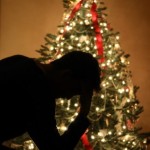 A shadow of a depressed man in front of a Christmas tree.