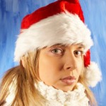A girl in a Santa hat looking sad.