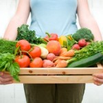 A woman holding a basket full of vegetables.