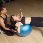 A woman doing dumbbell chest presses on a balance ball.