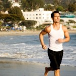 A male jogger jogging alone the beach.
