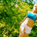 A woman jogging in a sunny forest.