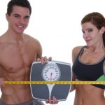 A healthy couple holding scales and a measuring tape.