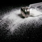 A spilled salt shaker on a black background.