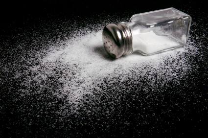 A spilled salt shaker on a black background.