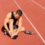 An injured runner sitting on a running track.