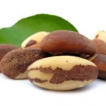 A selection of brazil nuts in front of a green leaf.
