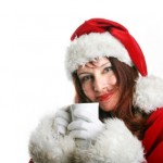 A woman in a Santa hat with a hot drink.