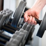 A hand lifting a dumbbell from a rack.
