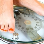 A close up of 2 feet on a pair of weighing scales.