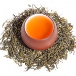 A cup of tea surrounded by tea leaves.