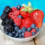A bowl of assorted berries next to a pool.