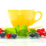 A cup of tea surrounded by a selection of berries.
