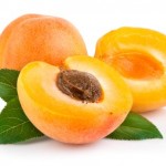 A whole and chopped apricot on a white background.