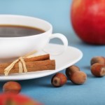 A cup of coffee an apple and some hazelnuts.