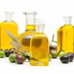 4 bottles of olive oil surrounded by olives.