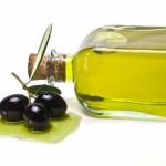 3 olives next to a glass bottle of olive oil.