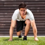 A male runner crouching down, getting ready to sprint.