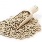 A pile of sunflower seeds with a scoop.