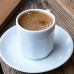 A cup of coffee on a wooden table.