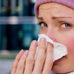 A woman with a cold blowing her nose.