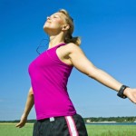 A woman outside after a run enjoying her music.