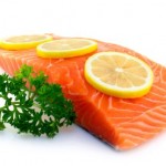 A piece of raw salmon garnished with lemon and parsley.