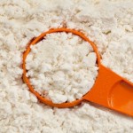 A large pile of protein powder with an orange scoop.