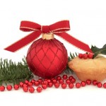 A mince pie next to a bauble and other Christmas decorations.