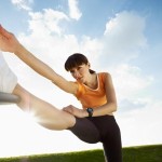 A woman stretching her right leg outside.