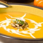 A bowl of creamy pumpkin soup topped with pumpkin seeds.