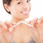 A smiling woman breaking a cigarette.